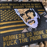 Olive Green and Black Embroidered patch with a man’s head in the middle and text above and below that reads Losers always whine about their best winners go home and fuck the prom queen