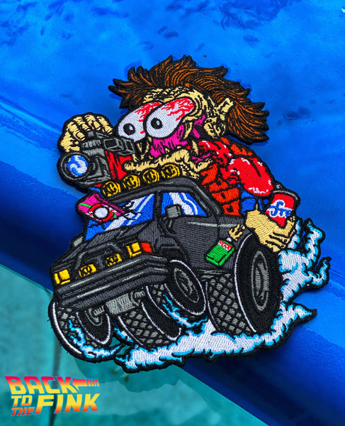 Embroidered patch featuring a bulging eyes style cartoon character driving a hot rod style black pick up truck vehicle 
