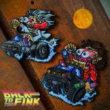 Two embroidered patches with each featuring a cartoon character with bulging eyes each driving a hot rod style vehicle
