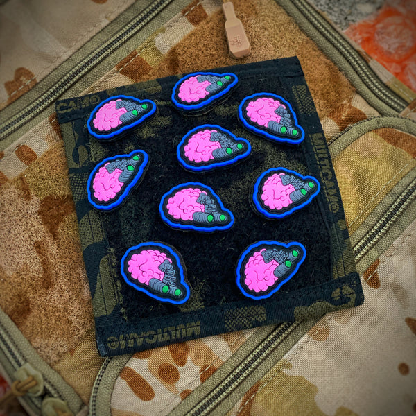Pvc rubber patch depicting a pink brain with night vision goggles attached to brain