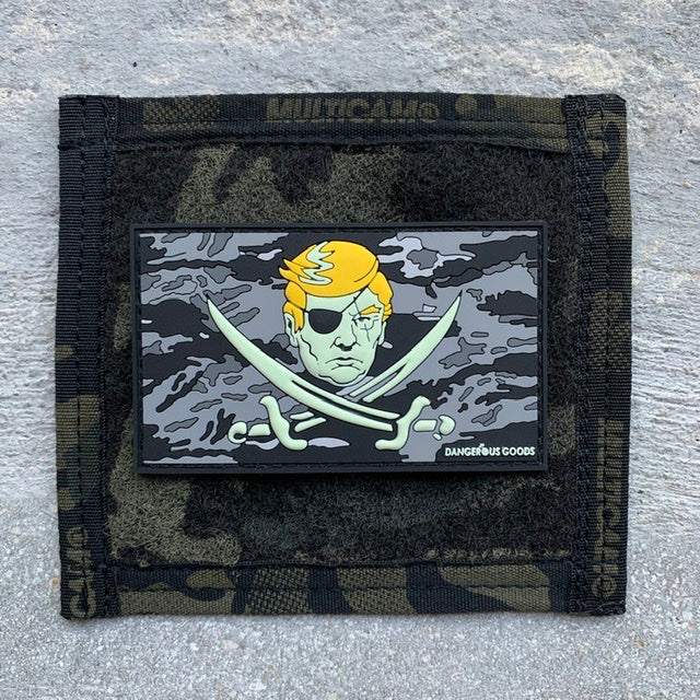 Black and grey tiger stripe camo style flag pvc rubber patch depicting a cartoon image of trumps head with two crossing pirate swords underneath 