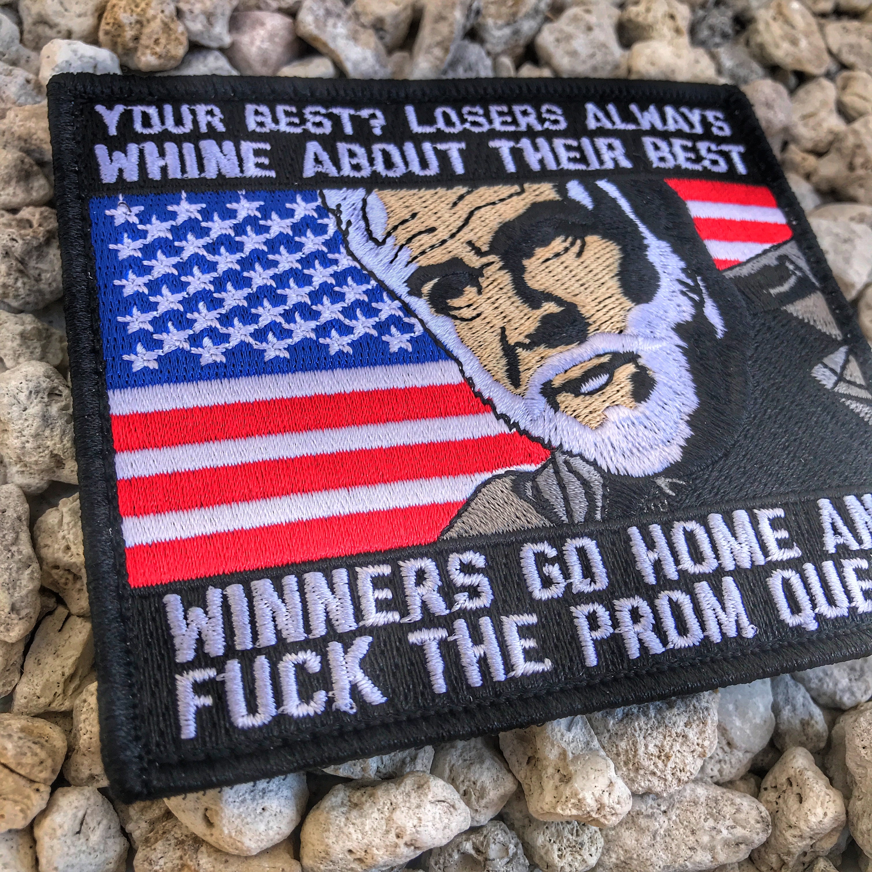 Red white and Blue Embroidered patch with a man’s head in the middle of American flag and text above and below that reads Losers always whine about their best winners go home and fuck the prom queen