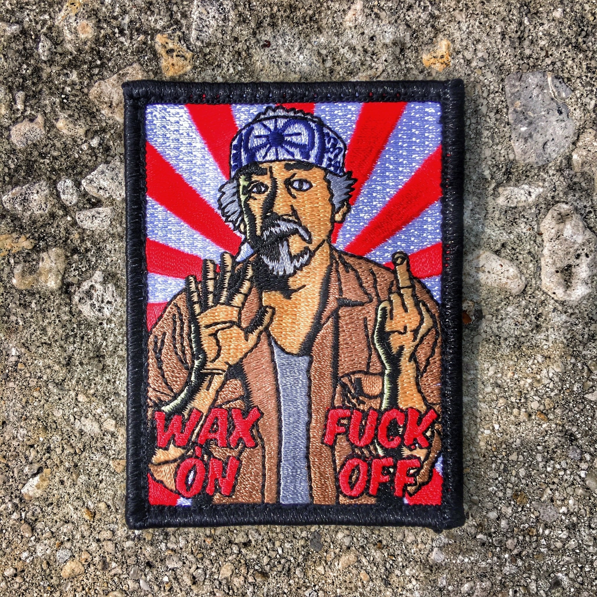 Embroidered patch with man holding up middle finger with text below that reads Wax On Fuck Off